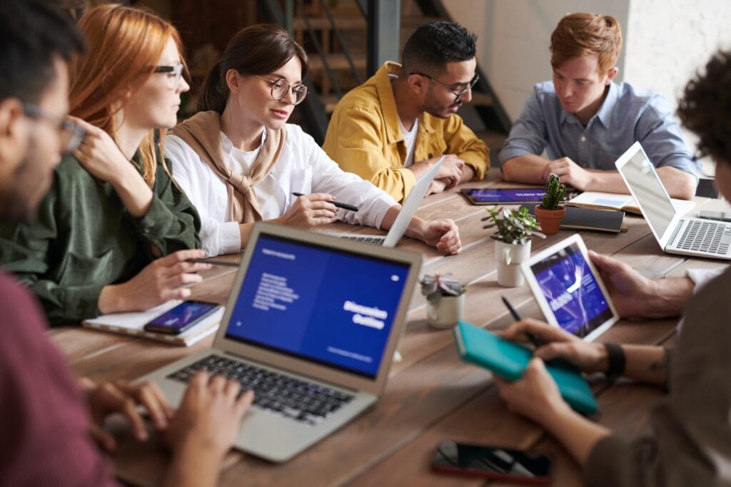 Diverse group working together while interacting with tablets and laptops