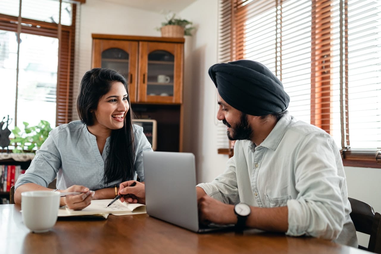 Woman and man sitting at table next to computer