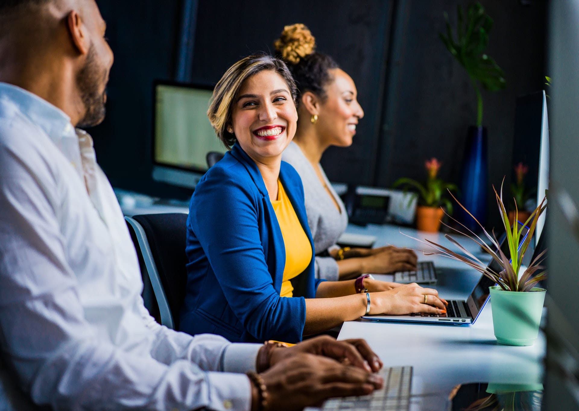 Three employees laughing and working together at a table