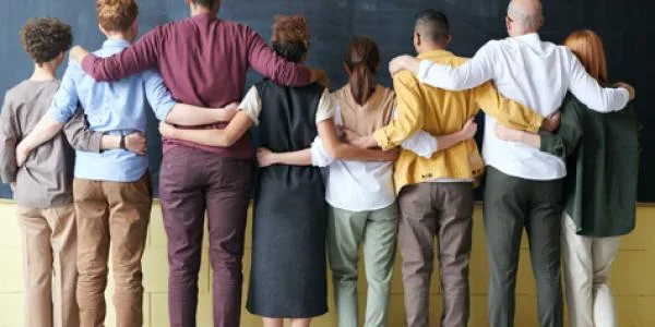 Group of people lined up and with their arms around the shoulder of the person next to them