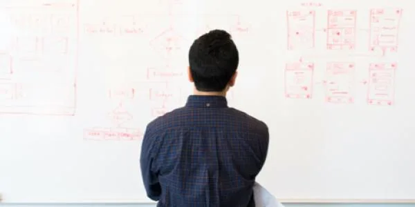 Man looking at the notes on a white board