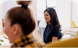 Two women laughing on couch during staff meeting