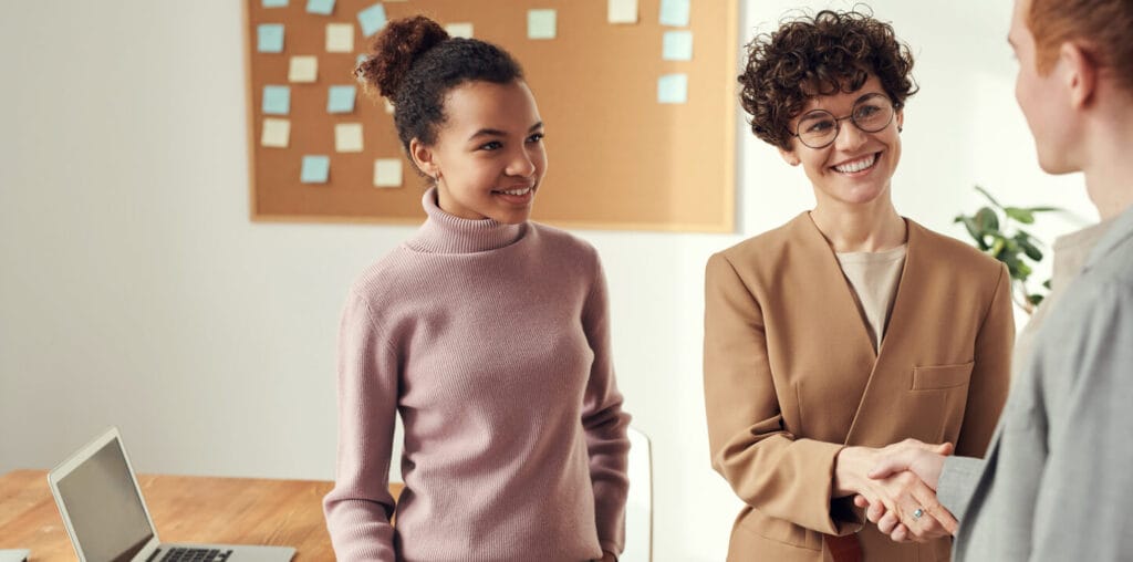 Woman handshaking another person and smiling