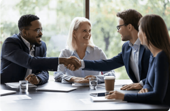 two men shaking hands, 2 women sitting on either side of one of the men