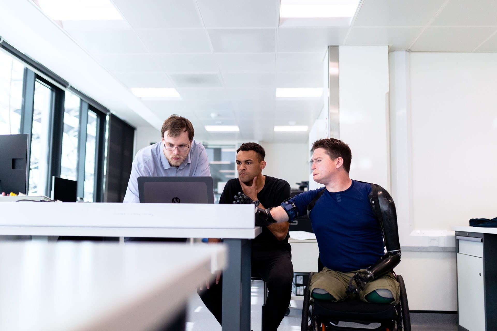 3 men looking at laptop at work station
