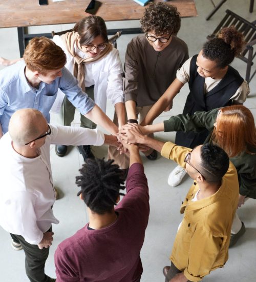 Diverse group forming a circle with their hands on the center